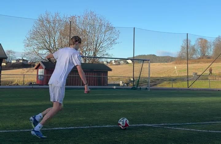 Filmed from behind and a little to the side: the player in his run-up, the ball at rest and the whole goal in the picture