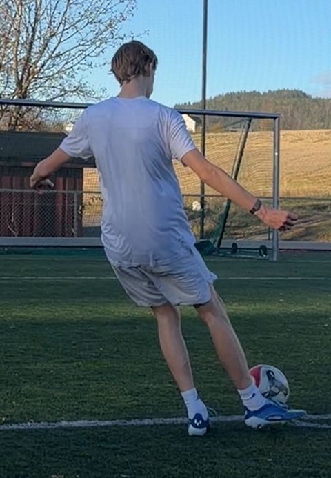 From behind at the strike: the shooting foot at the ball, upper body upright